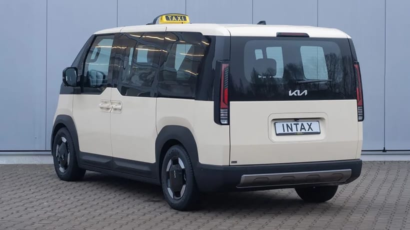 Kia PV5 Passenger Taxi vor einem  Gebäude in Hinteransicht