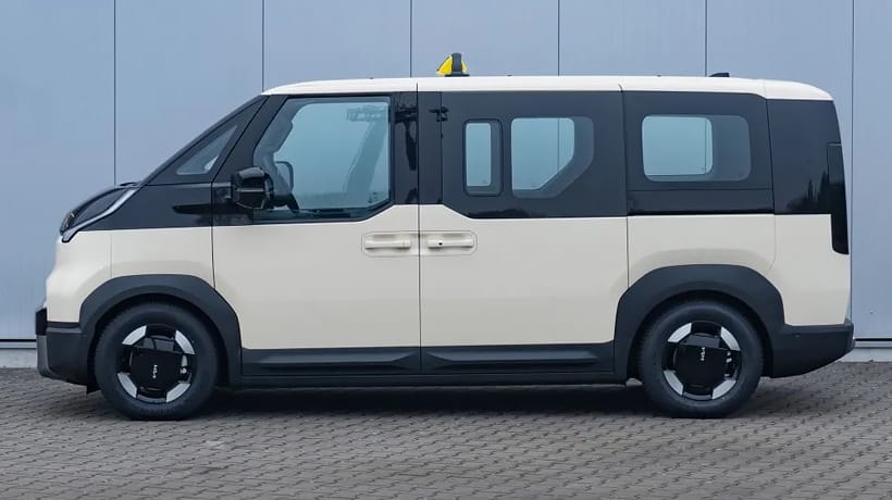 Kia PV5 Passenger Taxi vor einem  Gebäude in Seitenansicht
